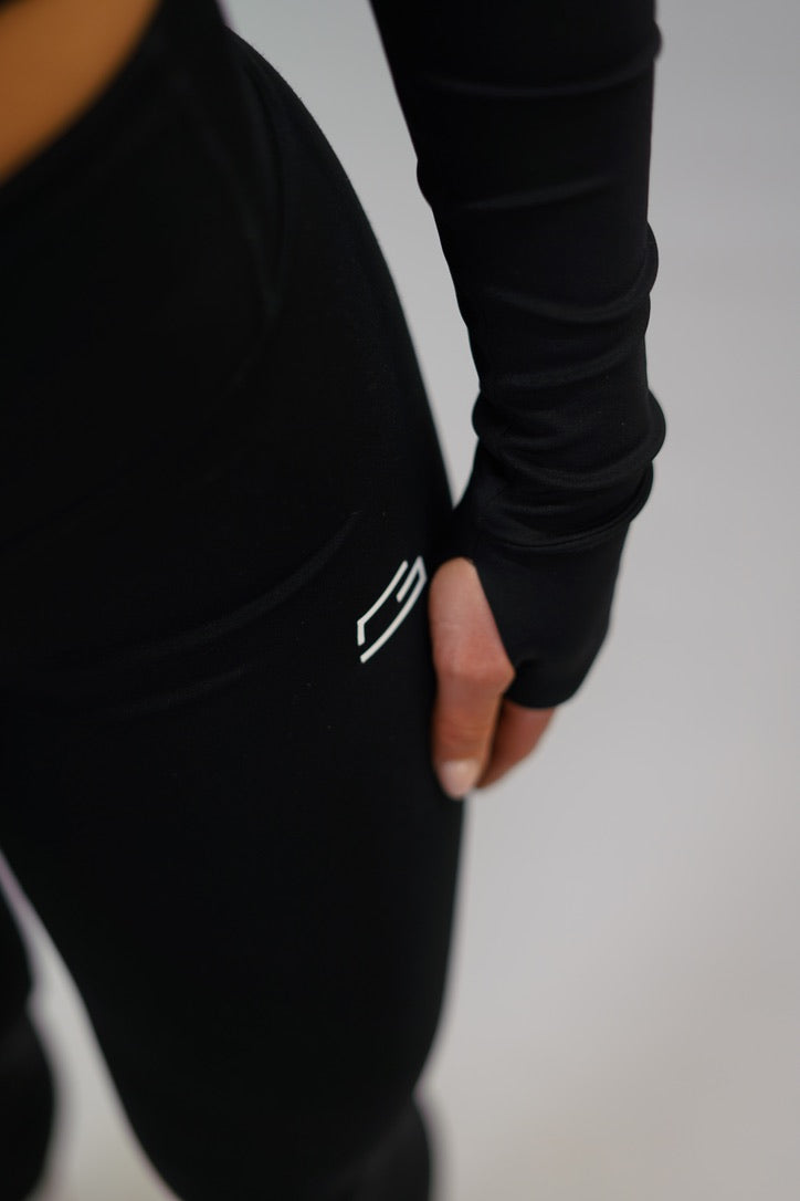 Svart Zoe Cropped Zip-up Top - cropped långärmad tröja med dragkedja, tumhål, Gymwear-logga på vänster axel och G-symbol i nacken