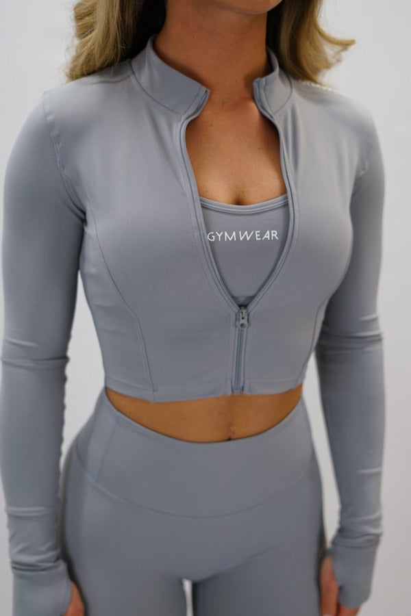 Ljusgrå Zoe Cropped Zip-up Top - cropped långärmad tröja med dragkedja, tumhål, Gymwear-logga på vänster axel och G-symbol i nacken