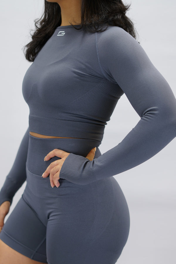 Grå Celia Long-Sleeve Crop Top, en cropped långärmad träningströja med G-symbol på framsidan och Gymwear-logotyp baktill