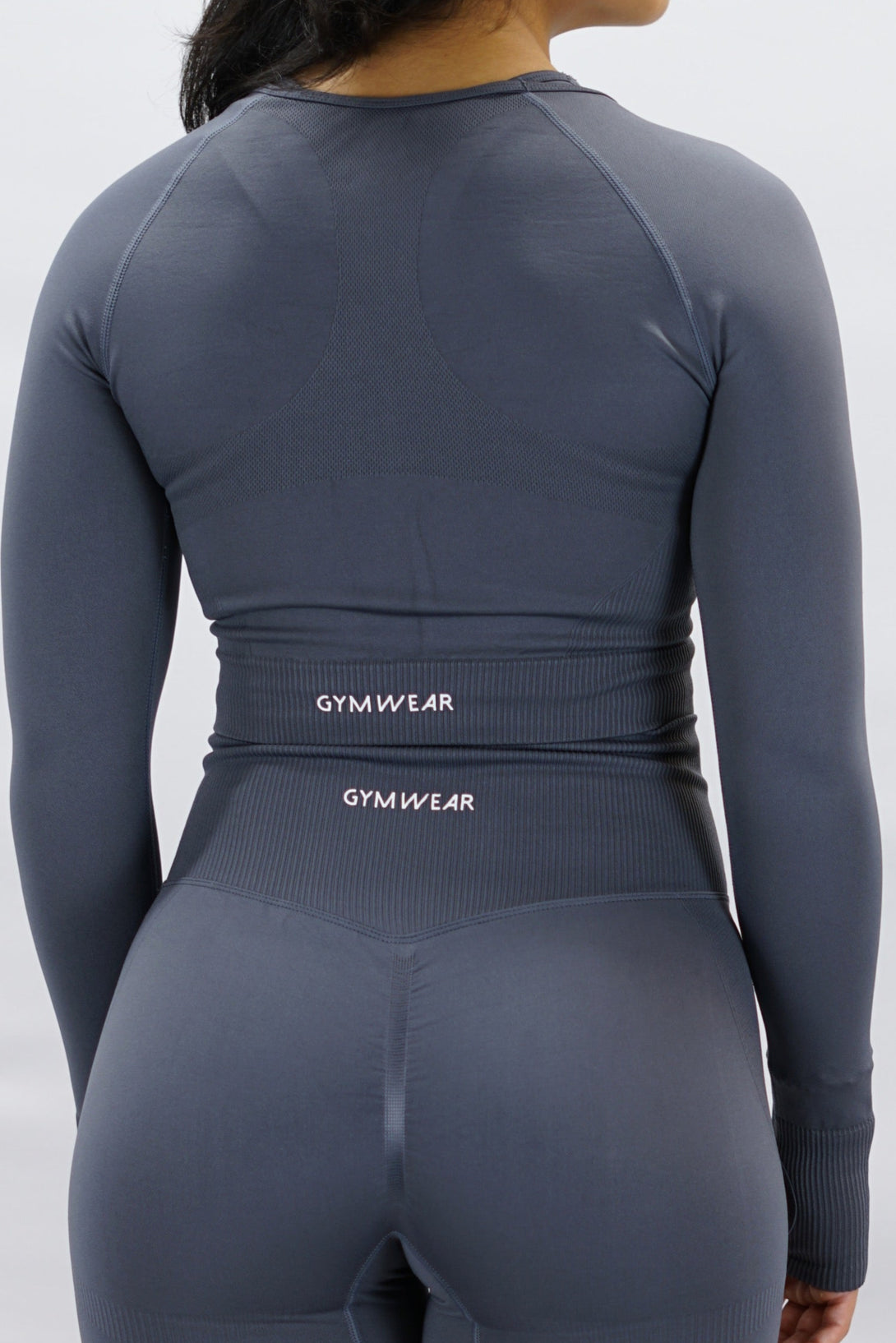 Grå Celia Long-Sleeve Crop Top, en cropped långärmad träningströja med G-symbol på framsidan och Gymwear-logotyp baktill