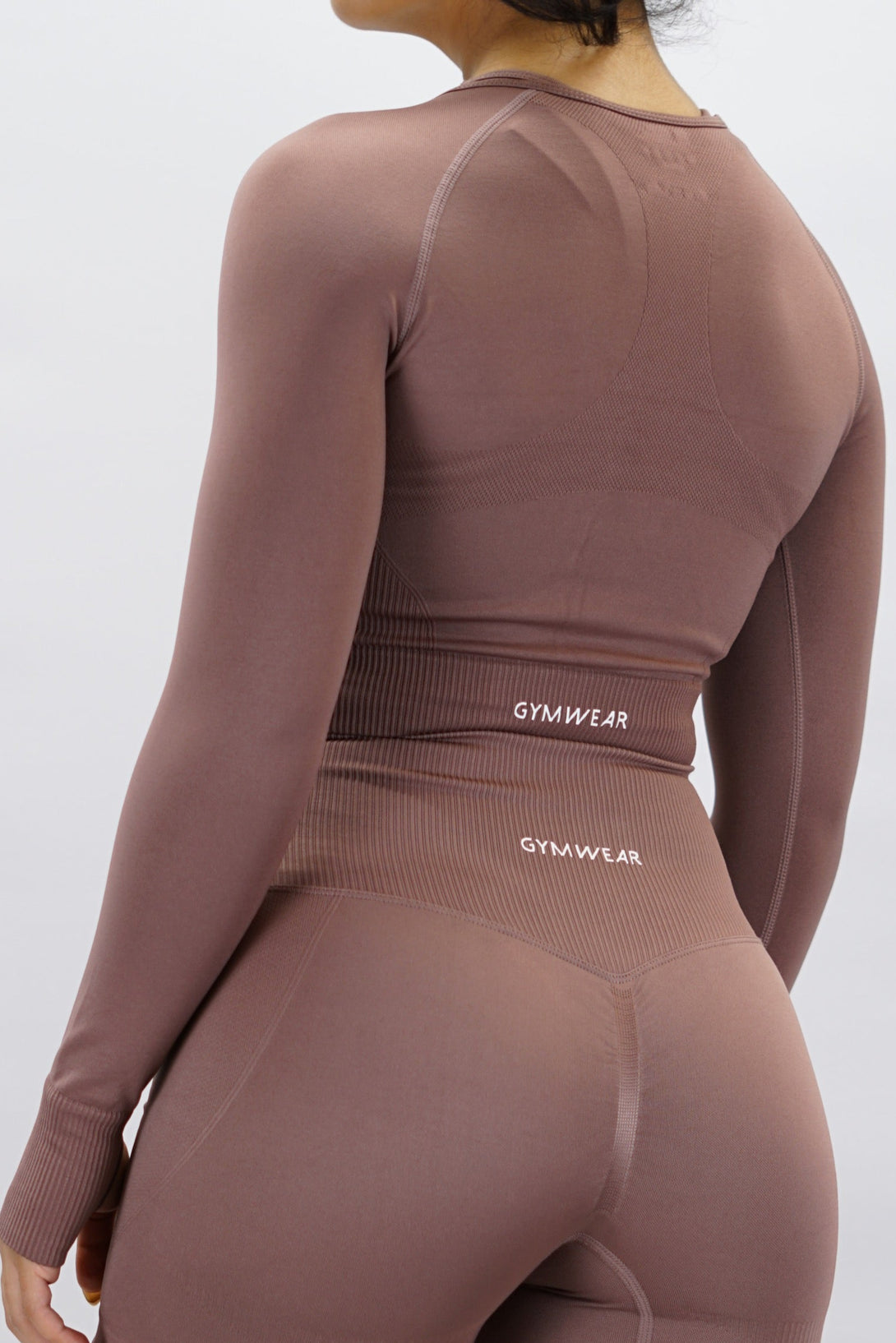 Gammaldags rosa Celia Long-Sleeve Crop Top, en cropped långärmad träningströja med G-symbol på framsidan och Gymwear-logotyp baktill