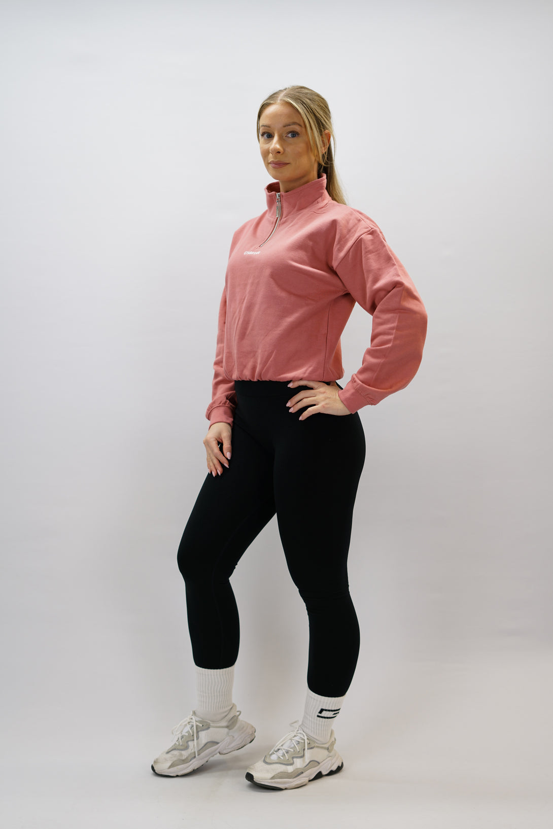 Gammaldags rosa Delia Half-Zip Long Sleeve, en långärmad tröja i 100% bomull med halvdragkedja vid halsen och diskret ton-i-ton Gymwear-logotyp centrerat på bröstet.