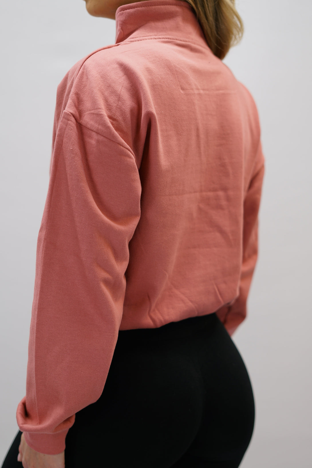 Gammaldags rosa Delia Half-Zip Long Sleeve, en långärmad tröja i 100% bomull med halvdragkedja vid halsen och diskret ton-i-ton Gymwear-logotyp centrerat på bröstet.