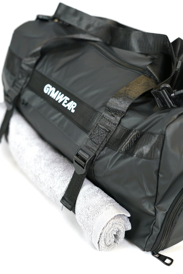 GYMWEAR Gym Bag svart, är en stilren och rymlig gym väska med smarta fack för skor, yoga matta, axelrem och vanlig handgrepp mm. Den är perfekt för att ta med sig allt som behövs till gymmet. Väskan är av hög kvalitet och tålig, vilket gör den till en bra investering för alla liten gymwear logo i center av väskan gym entusiaster.