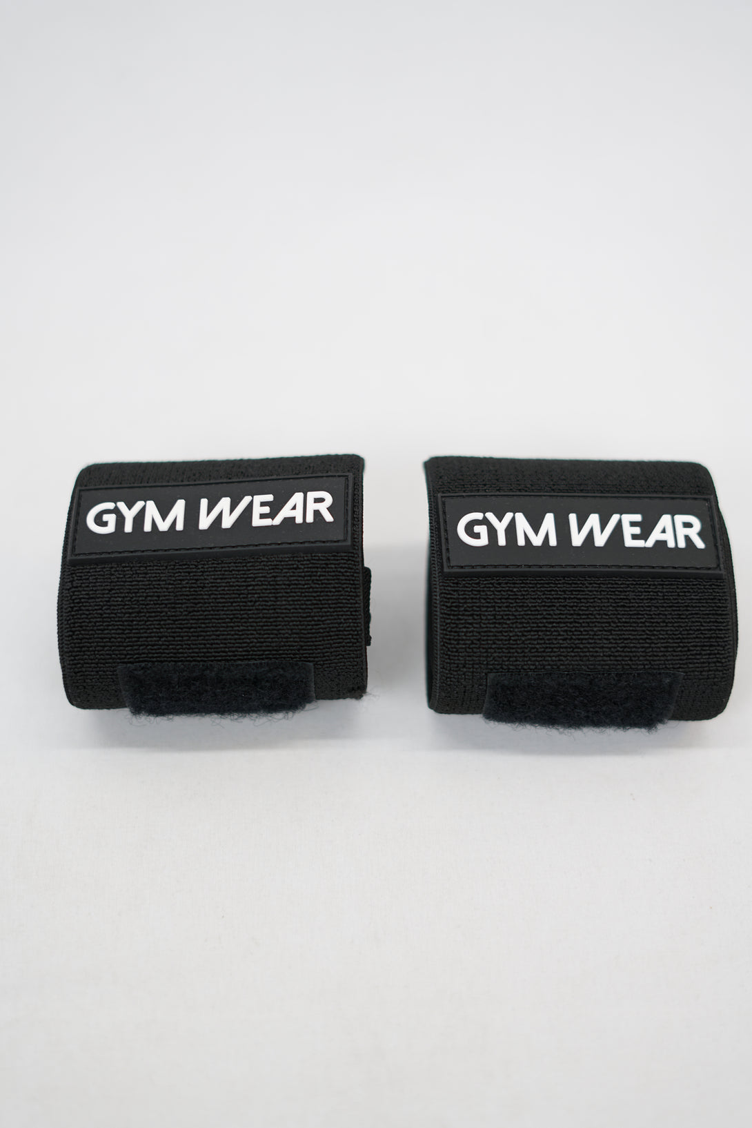 Svart GYMWEAR Wrist Wraps är handleds linda designad för styrketräning, CrossFit, och gym. Den har en justerbar kompressionsstrumpa som ger skadeförebyggande stöd. 