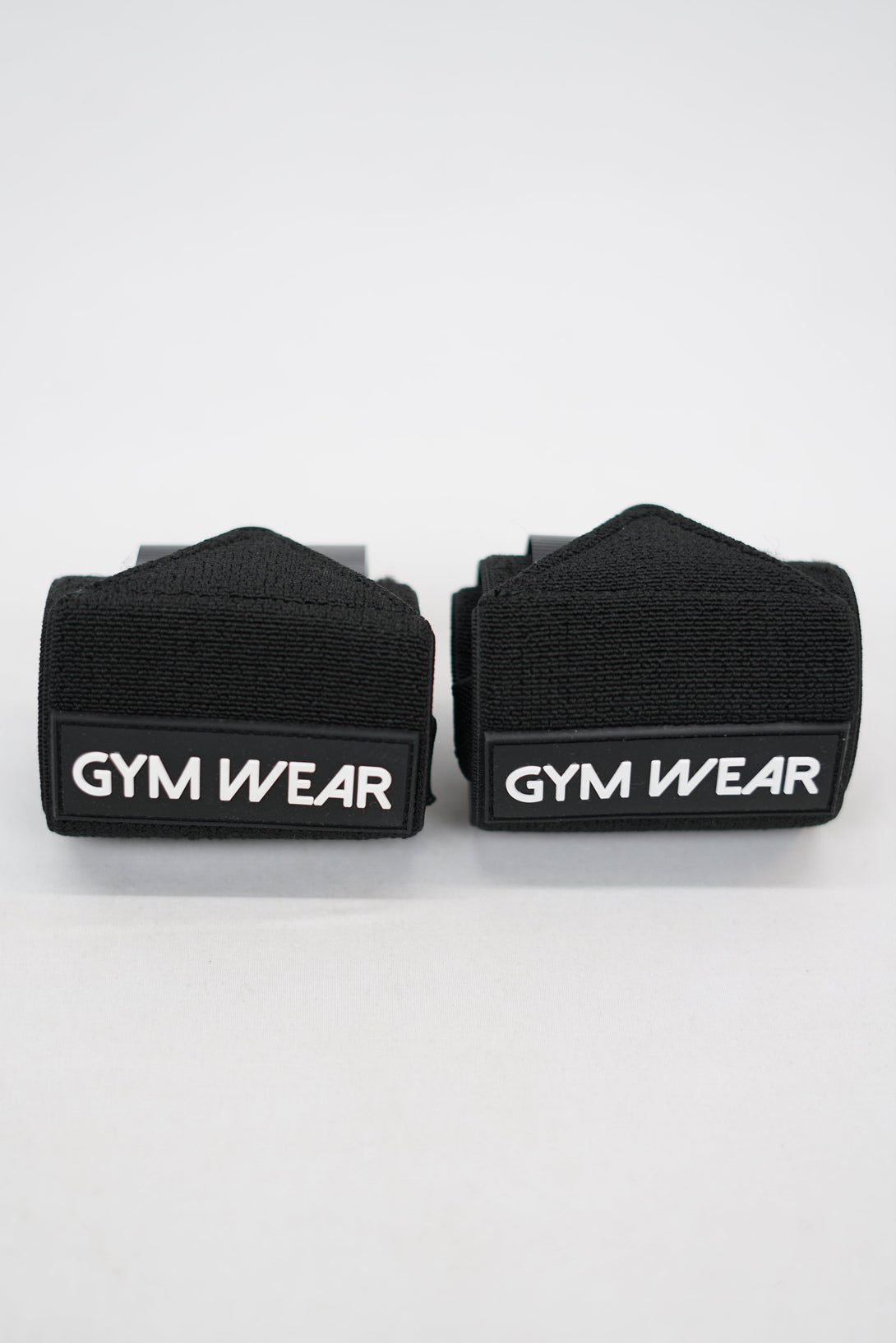Svart GYMWEAR Wrist Wraps är handleds linda designad för styrketräning, CrossFit, och gym. Den har en justerbar kompressionsstrumpa som ger skadeförebyggande stöd. 
