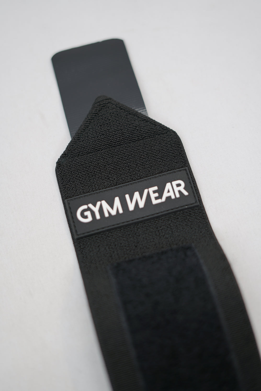 Svart GYMWEAR Wrist Wraps är handleds linda designad för styrketräning, CrossFit, och gym. Den har en justerbar kompressionsstrumpa som ger skadeförebyggande stöd. 