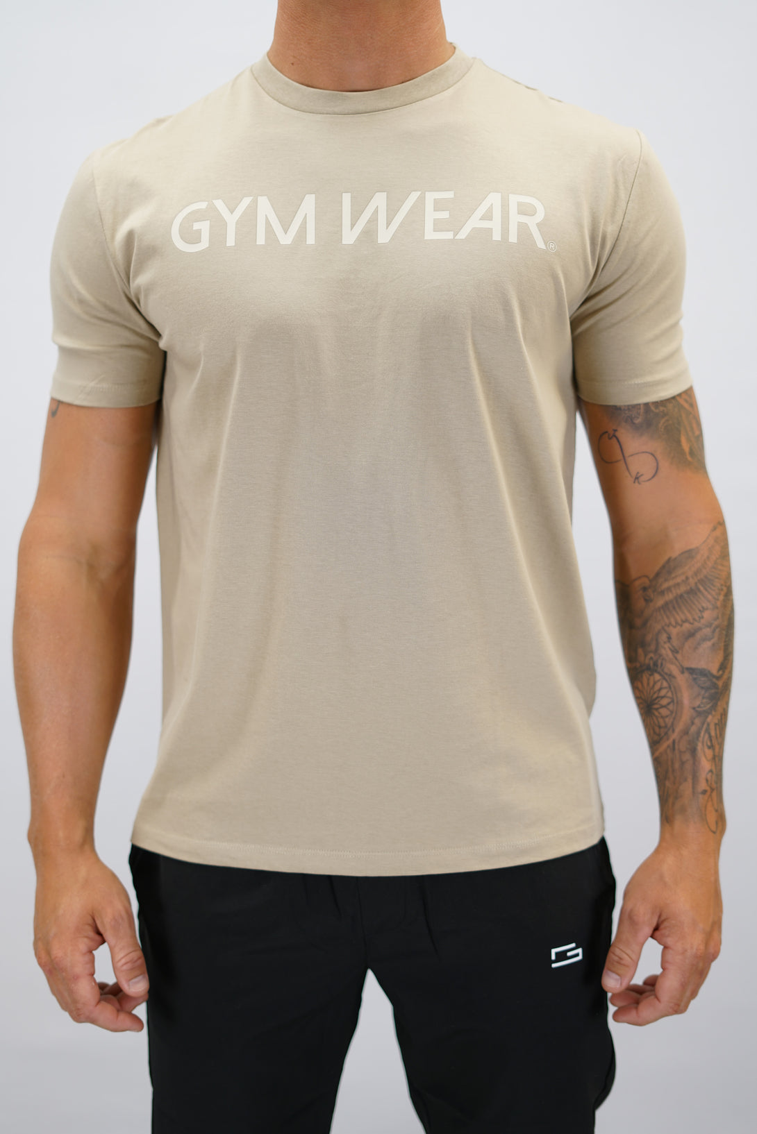 Brun+ Rion Organic Cotton T-shirt, en kortärmad tränings-t-shirt i ekologisk bomull med beige Gymwear-logotyp på bröstet och liten logga i nacken 