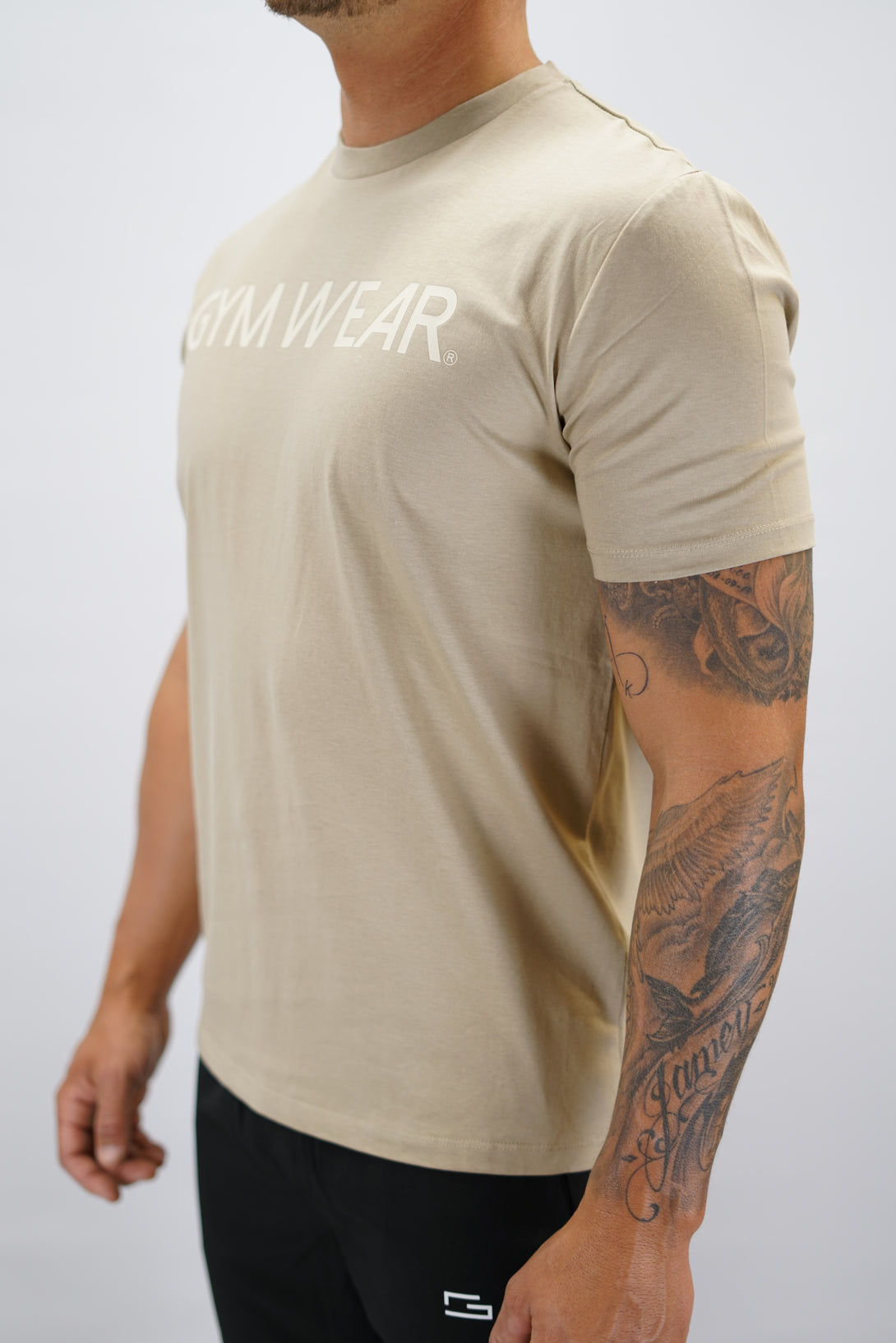 Brun+ Rion Organic Cotton T-shirt, en kortärmad tränings-t-shirt i ekologisk bomull med beige Gymwear-logotyp på bröstet och liten logga i nacken 