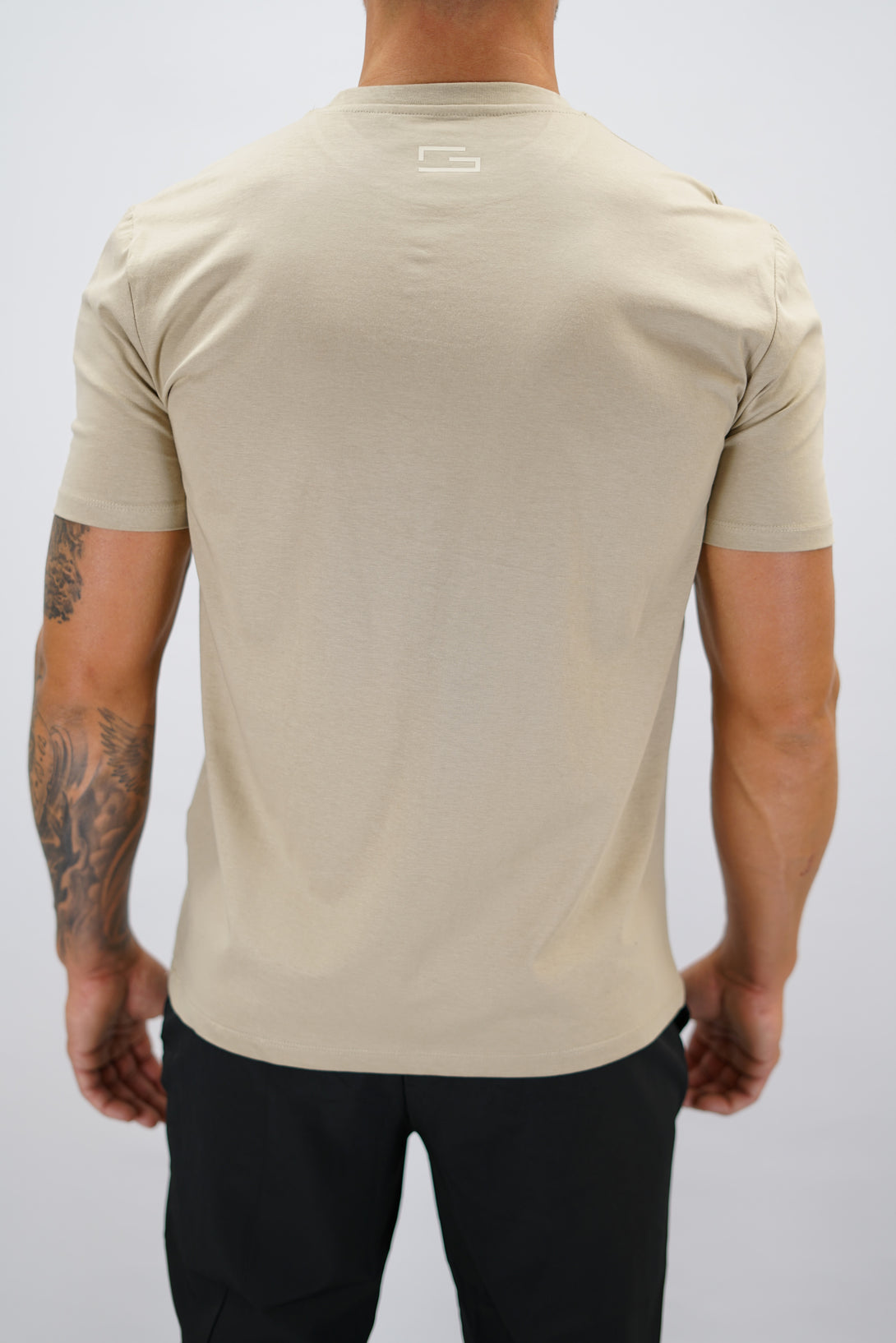Brun+ Rion Organic Cotton T-shirt, en kortärmad tränings-t-shirt i ekologisk bomull med beige Gymwear-logotyp på bröstet och liten logga i nacken 