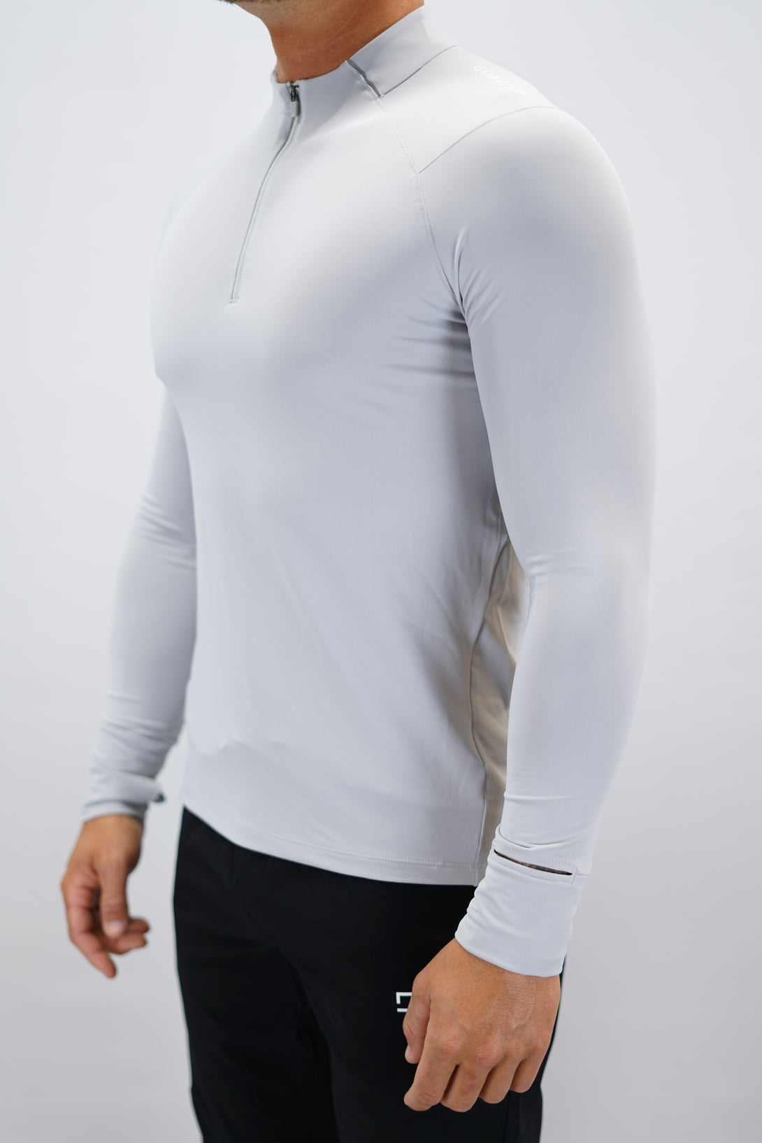 Ljusgrå Zayne Half-Zip Long Sleeve – Reflective Detail - långärmad träningströja med halvdragkedja, tumhål, klockutrymme, reflekterande detalj vid kragen och Gymwear-logga på framsidan