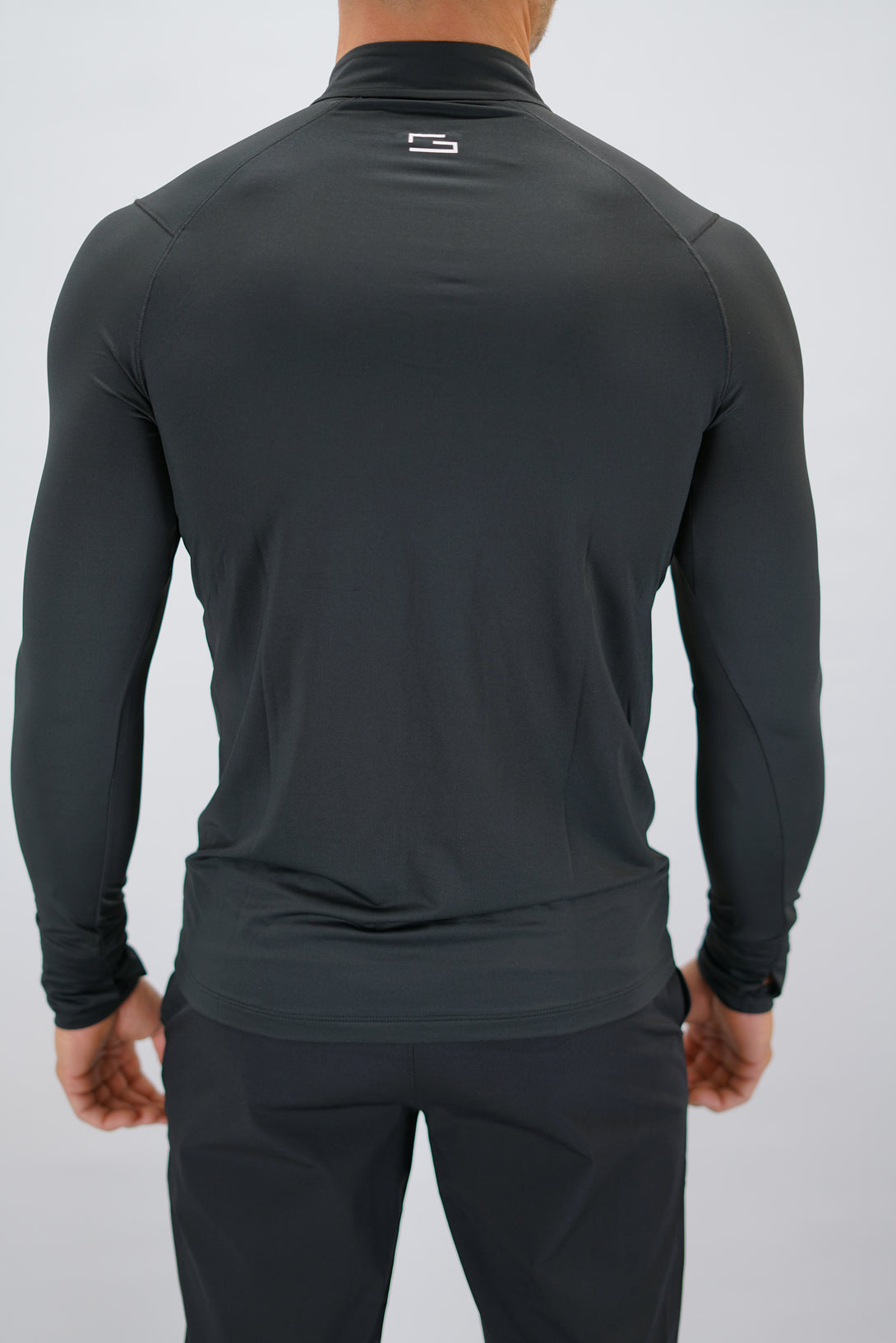 Svart Zayne Half-Zip Long Sleeve – Reflective Detail - långärmad träningströja med halvdragkedja, tumhål, klockutrymme, reflekterande detalj vid kragen och Gymwear-logga på framsidan