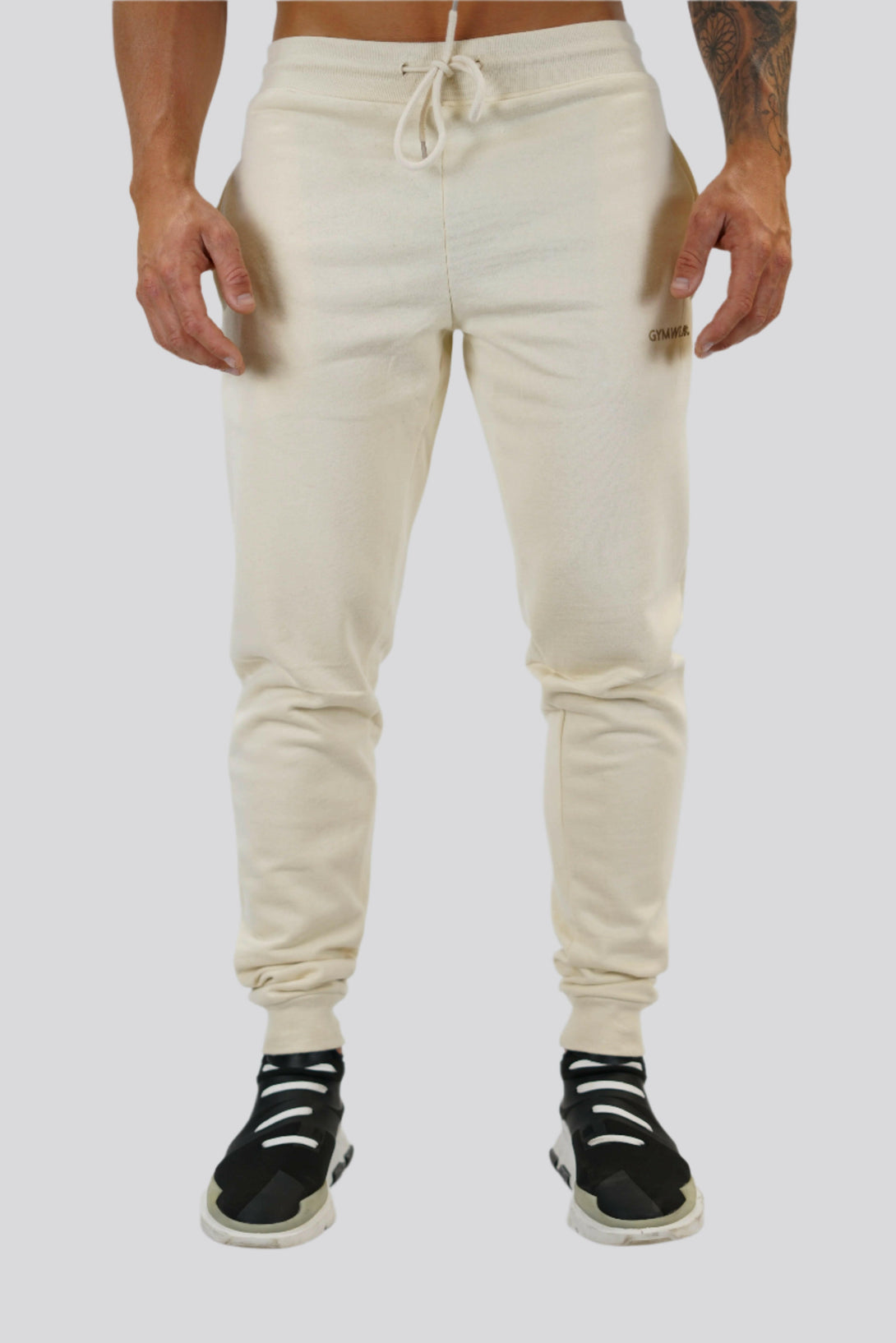 Bekväma JOGGER RAY i premium borstad bomull. Elastisk midja med dragsko, praktiska fickor och avsmalnande passform. Perfekt för träning och vardagsbruk. I färgen beige med Gymwear  logga på vänster lår.