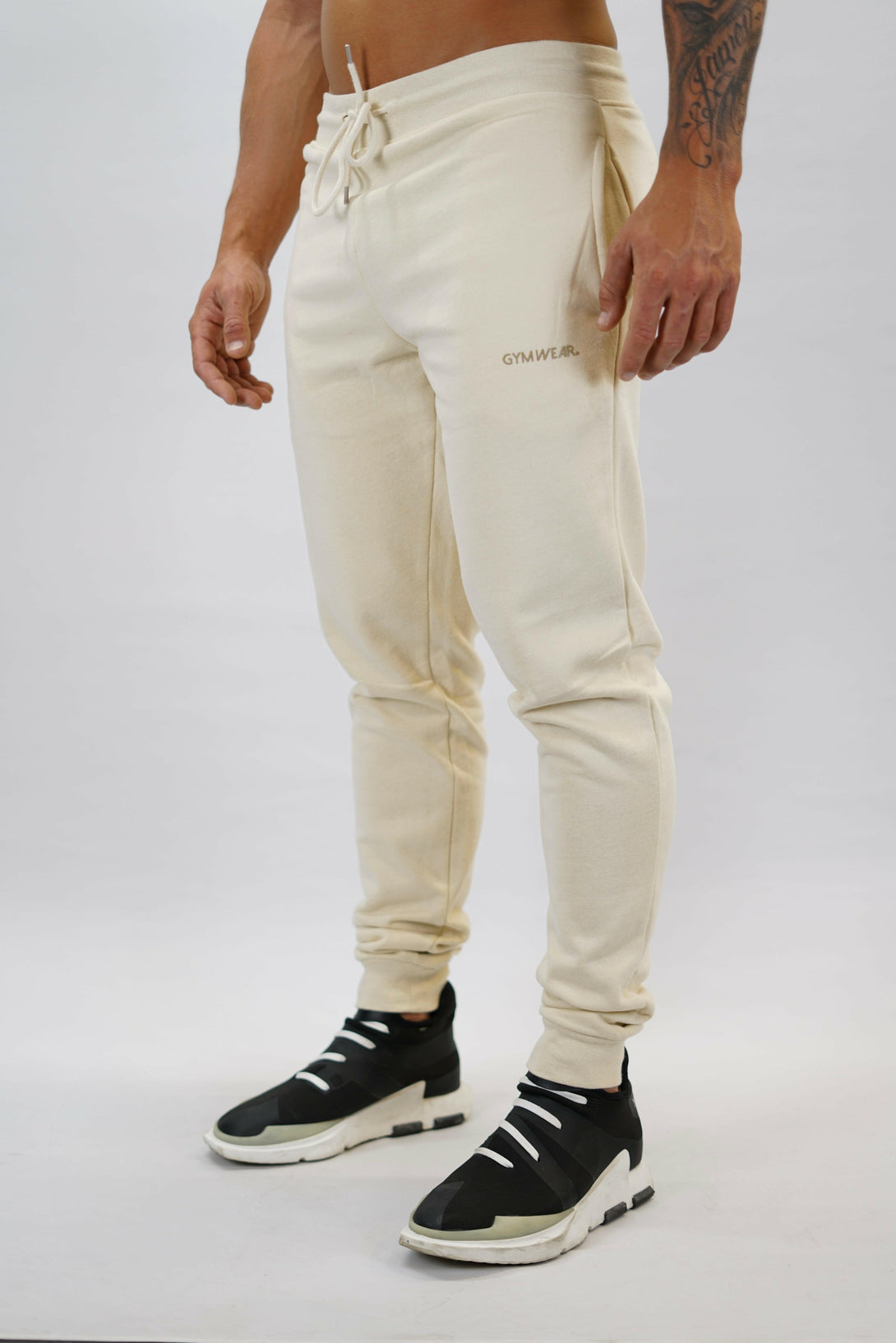 Bekväma JOGGER RAY i premium borstad bomull. Elastisk midja med dragsko, praktiska fickor och avsmalnande passform. Perfekt för träning och vardagsbruk. I färgen beige med Gymwear  logga på vänster lår.