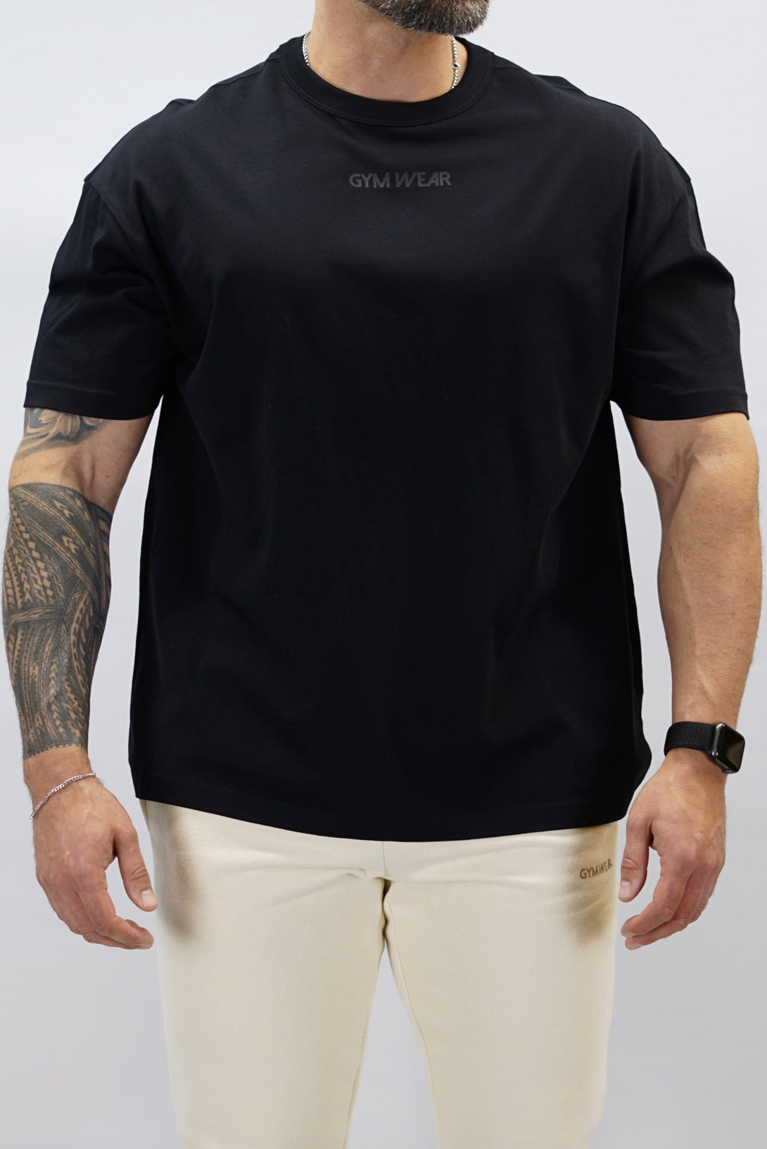 Svart Mino Organic Oversized T-Shirt, en oversized tränings-t-shirt i skönt och svalt organiskt material med Gymwear-logotyp centrerat på bröstet och G-symbol i nacken