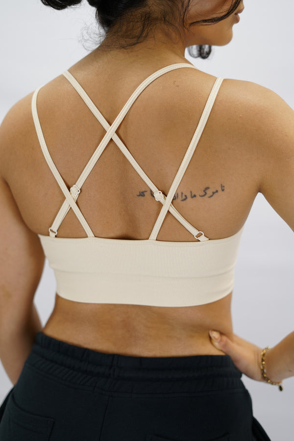 Beige Eily Cross Bra - sport-bh med korsade axelband baktill och Gymwear-logga på vänster nedre kant