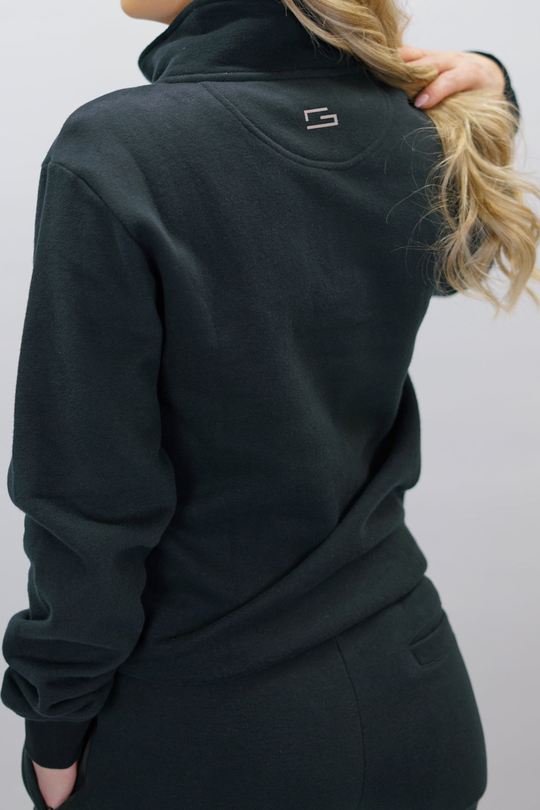 Half-Zip Sweater för dam i mjuk borstad bomull, svart färg, med logga på vänster bröst och symbol i nacken. Stilren och funktionell tröja för vardag och aktivitet.