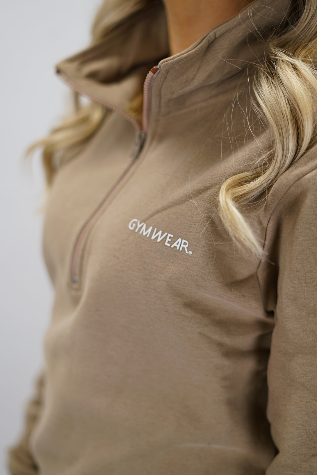 Half-Zip Sweater för dam i mjuk borstad bomull, brun färg, med logga på vänster bröst och symbol i nacken. Stilren och funktionell tröja för vardag och aktivitet.