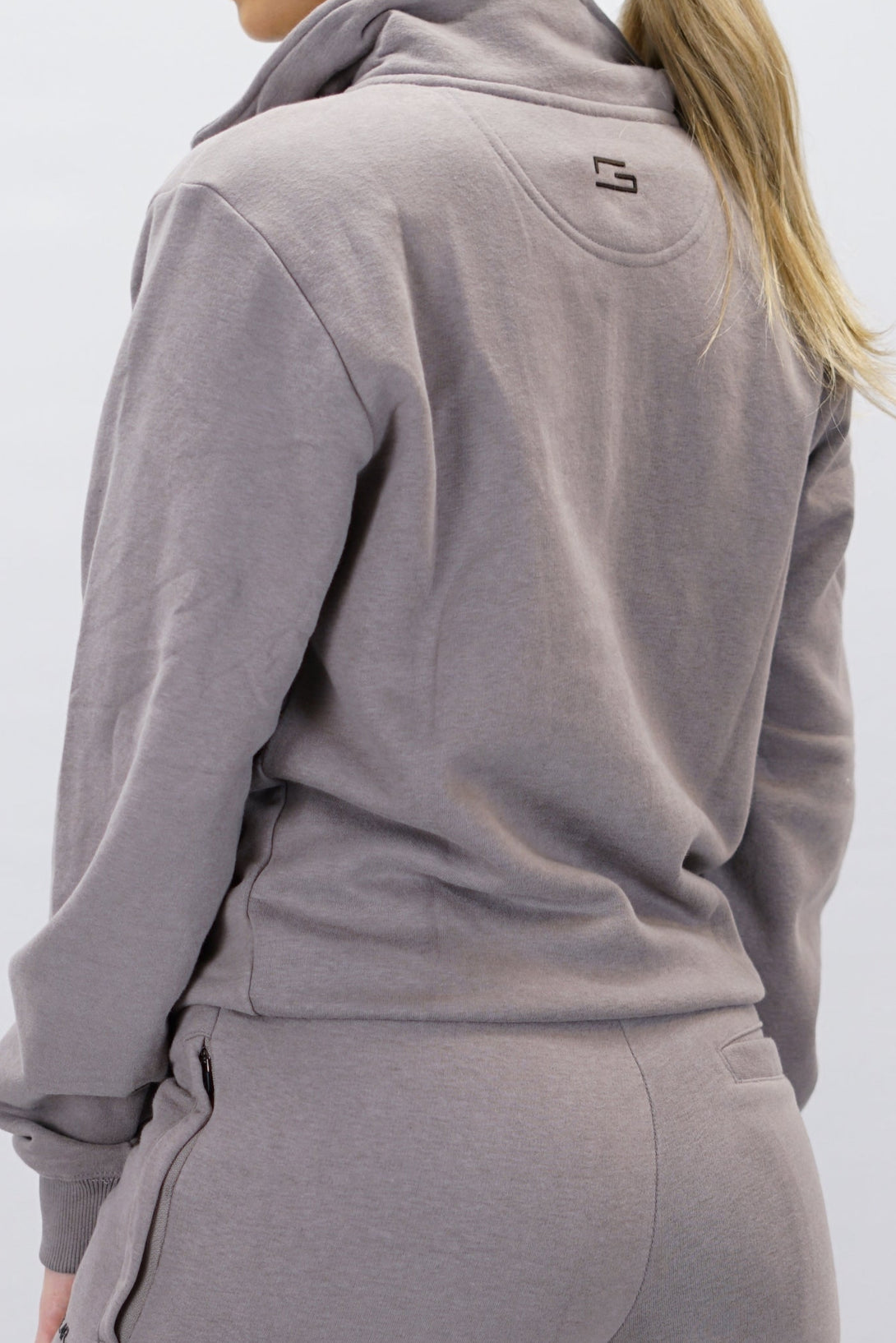Half-Zip Sweater för dam i mjuk borstad bomull, zink färg, med logga på vänster bröst och symbol i nacken. Stilren och funktionell tröja för vardag och aktivitet.