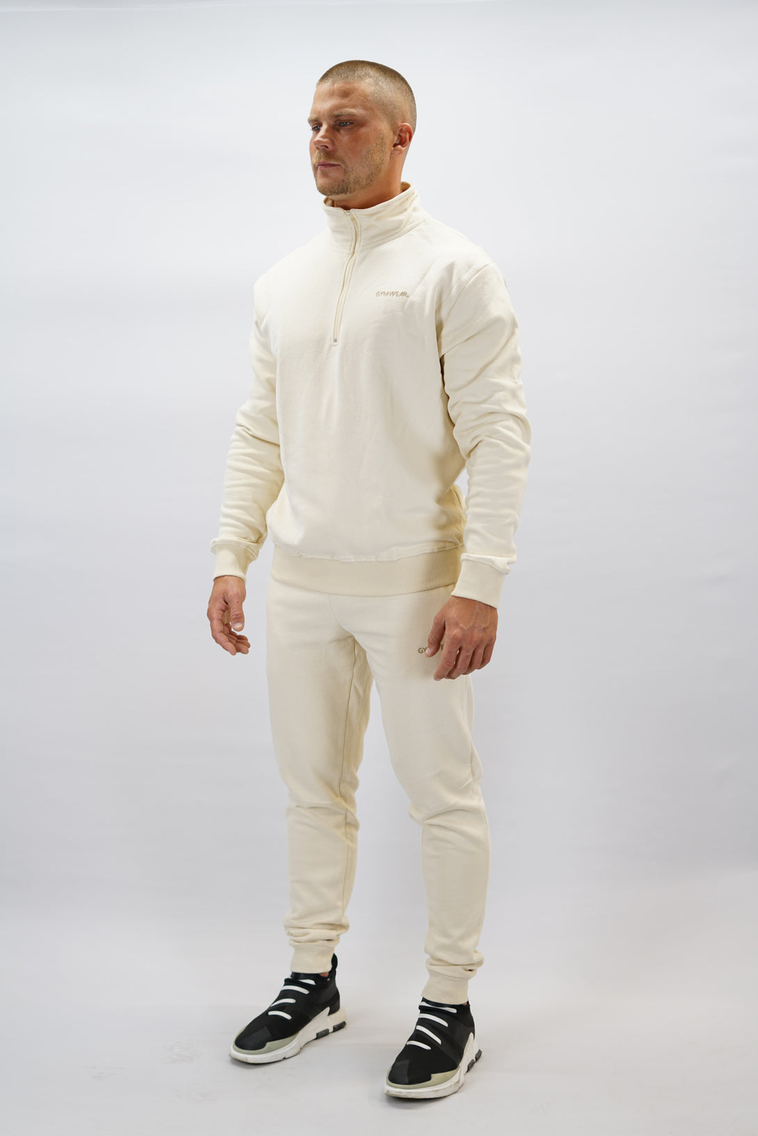 Half-Zip Sweater för herr i mjuk borstad bomull, beige färg, med Gymwear logga på vänster bröst och symbol G i nacken. Stilren och funktionell tröja för vardag och aktivitet.