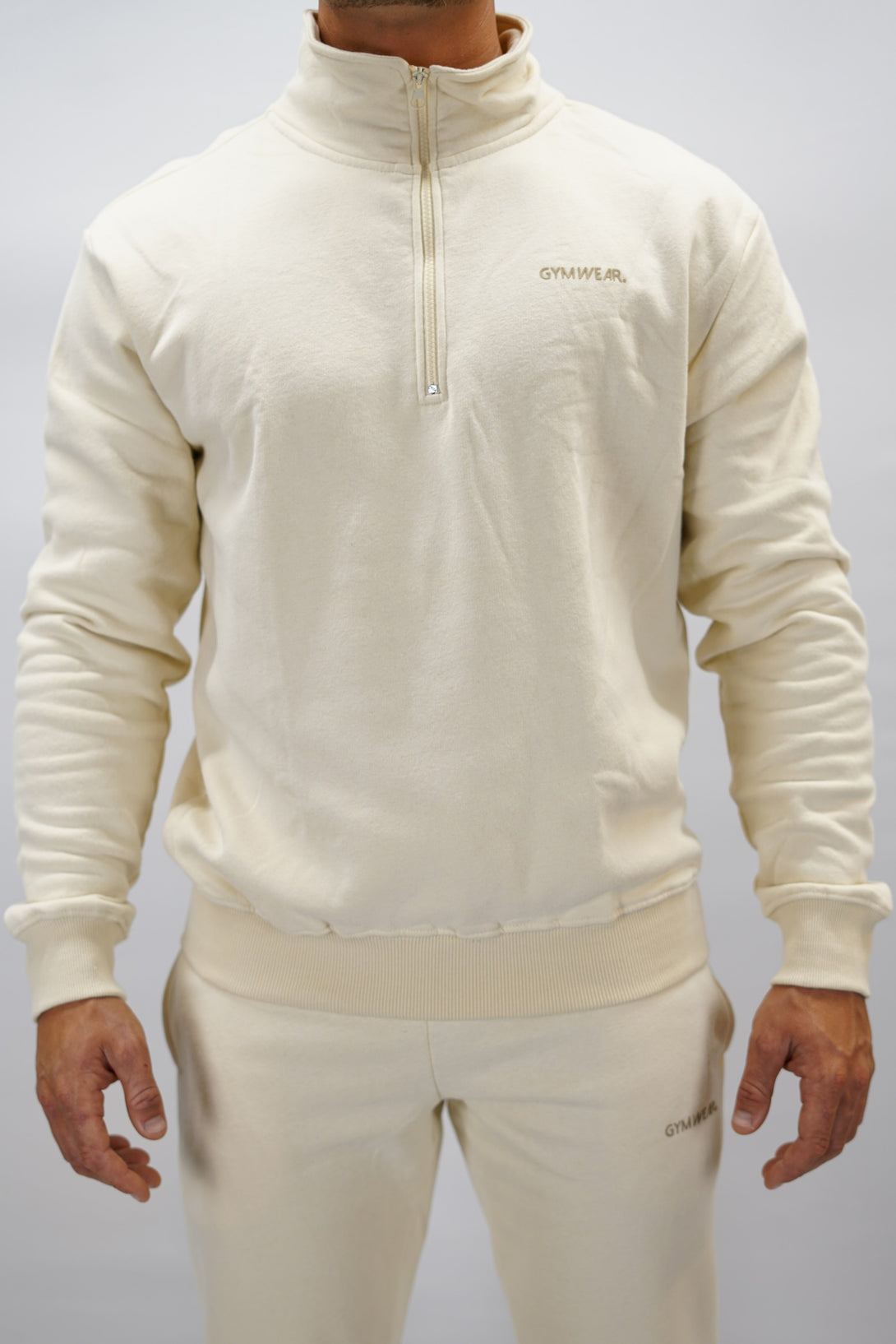 Half-Zip Sweater för herr i mjuk borstad bomull, beige färg, med Gymwear logga på vänster bröst och symbol G i nacken. Stilren och funktionell tröja för vardag och aktivitet.