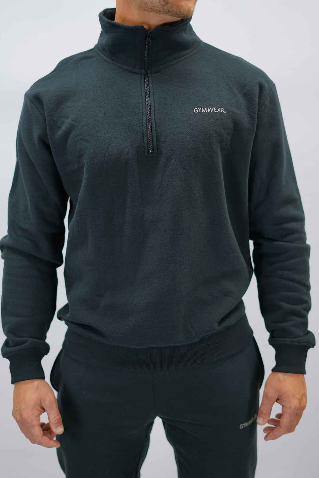 Half-Zip Sweater för herr i mjuk borstad bomull, svart färg, med Gymwear logga på vänster bröst och symbol G i nacken. Stilren och funktionell tröja för vardag och aktivitet.