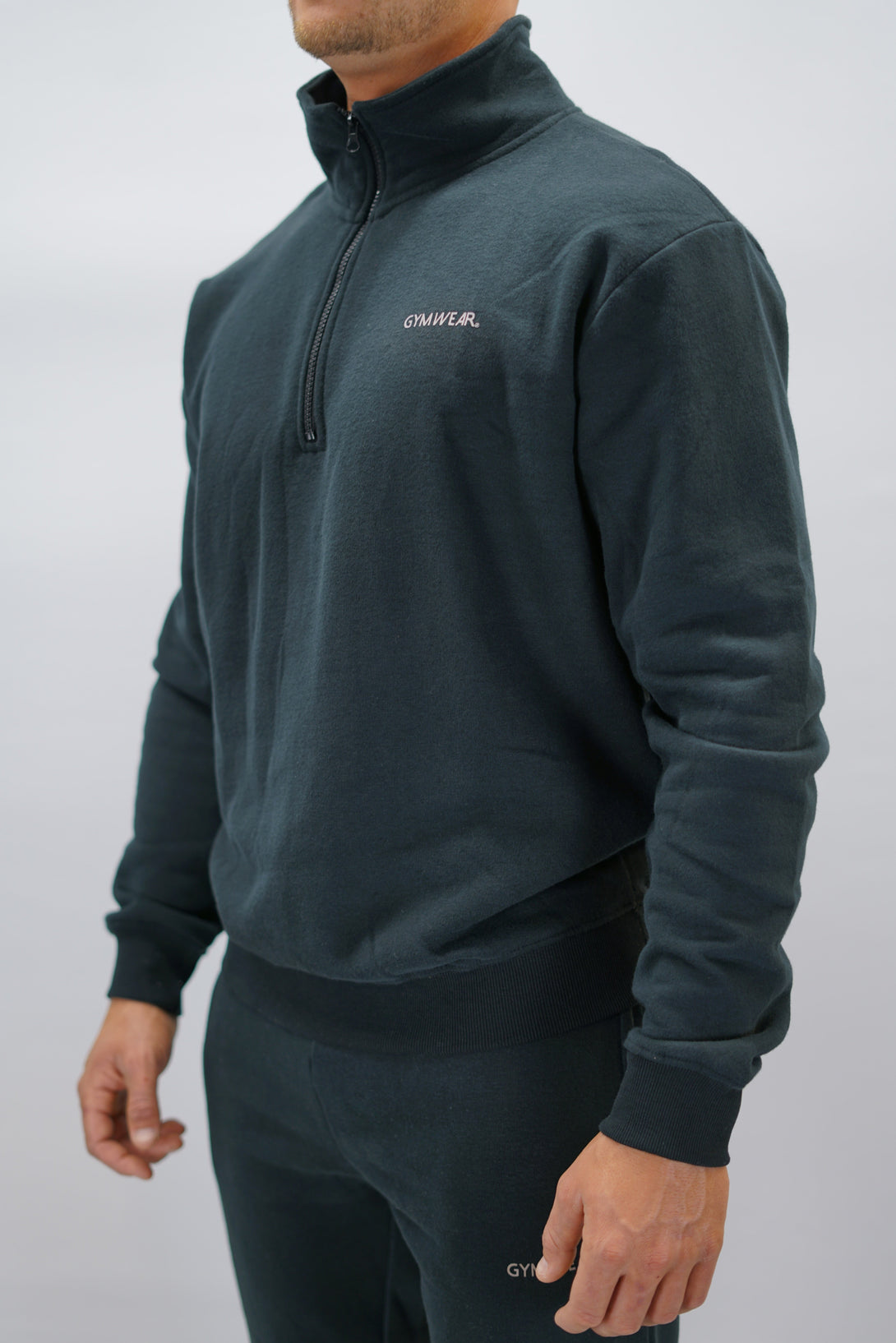 Half-Zip Sweater för herr i mjuk borstad bomull, svart färg, med Gymwear logga på vänster bröst och symbol G i nacken. Stilren och funktionell tröja för vardag och aktivitet.
