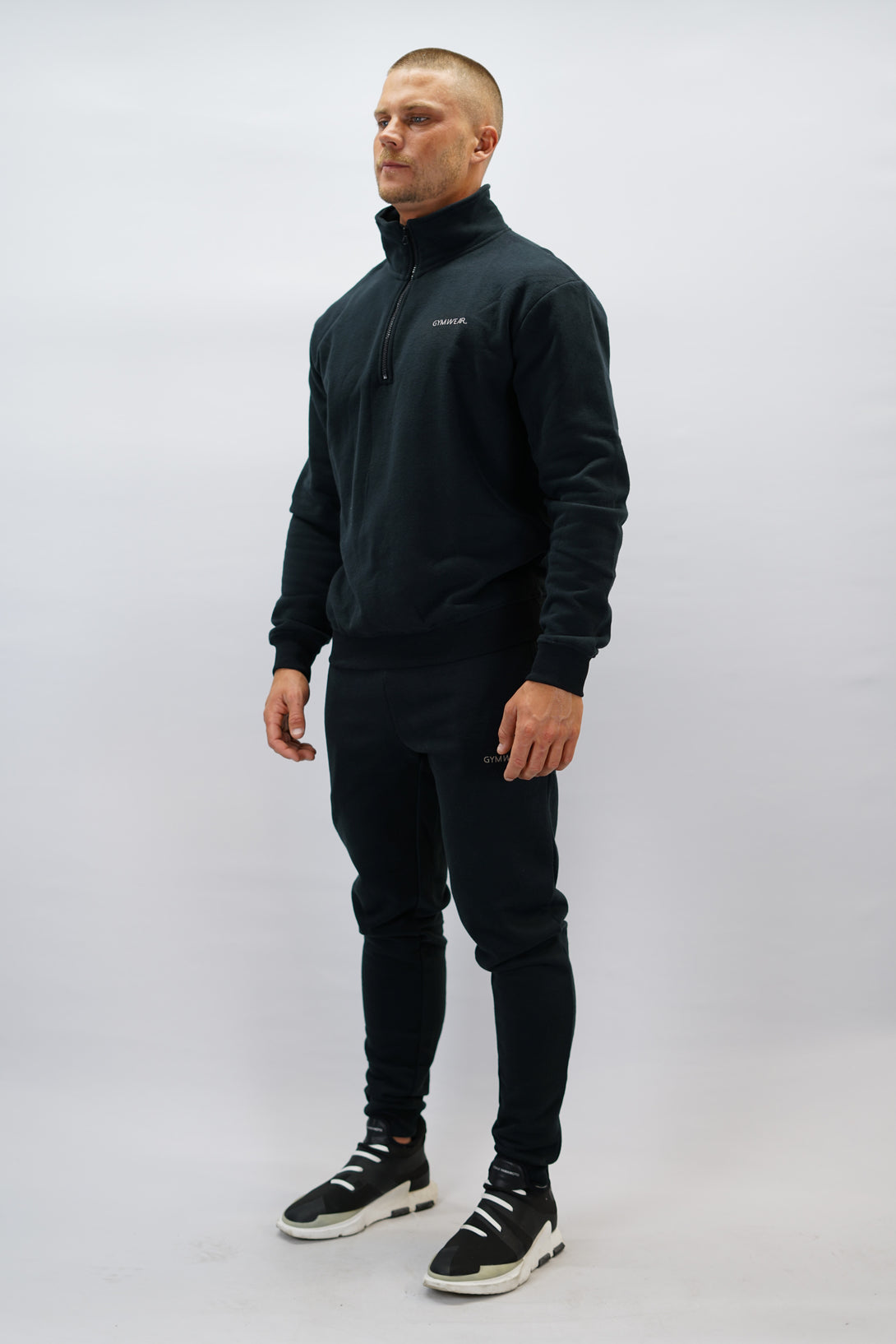 Half-Zip Sweater för herr i mjuk borstad bomull, svart färg, med Gymwear logga på vänster bröst och symbol G i nacken. Stilren och funktionell tröja för vardag och aktivitet.