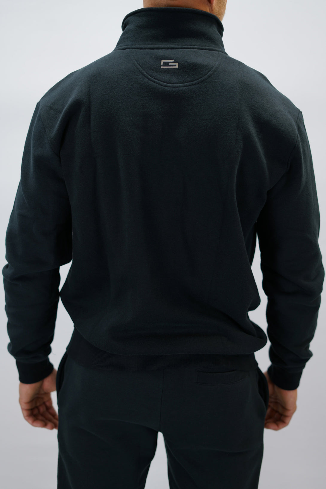 Half-Zip Sweater för herr i mjuk borstad bomull, svart färg, med Gymwear logga på vänster bröst och symbol G i nacken. Stilren och funktionell tröja för vardag och aktivitet.