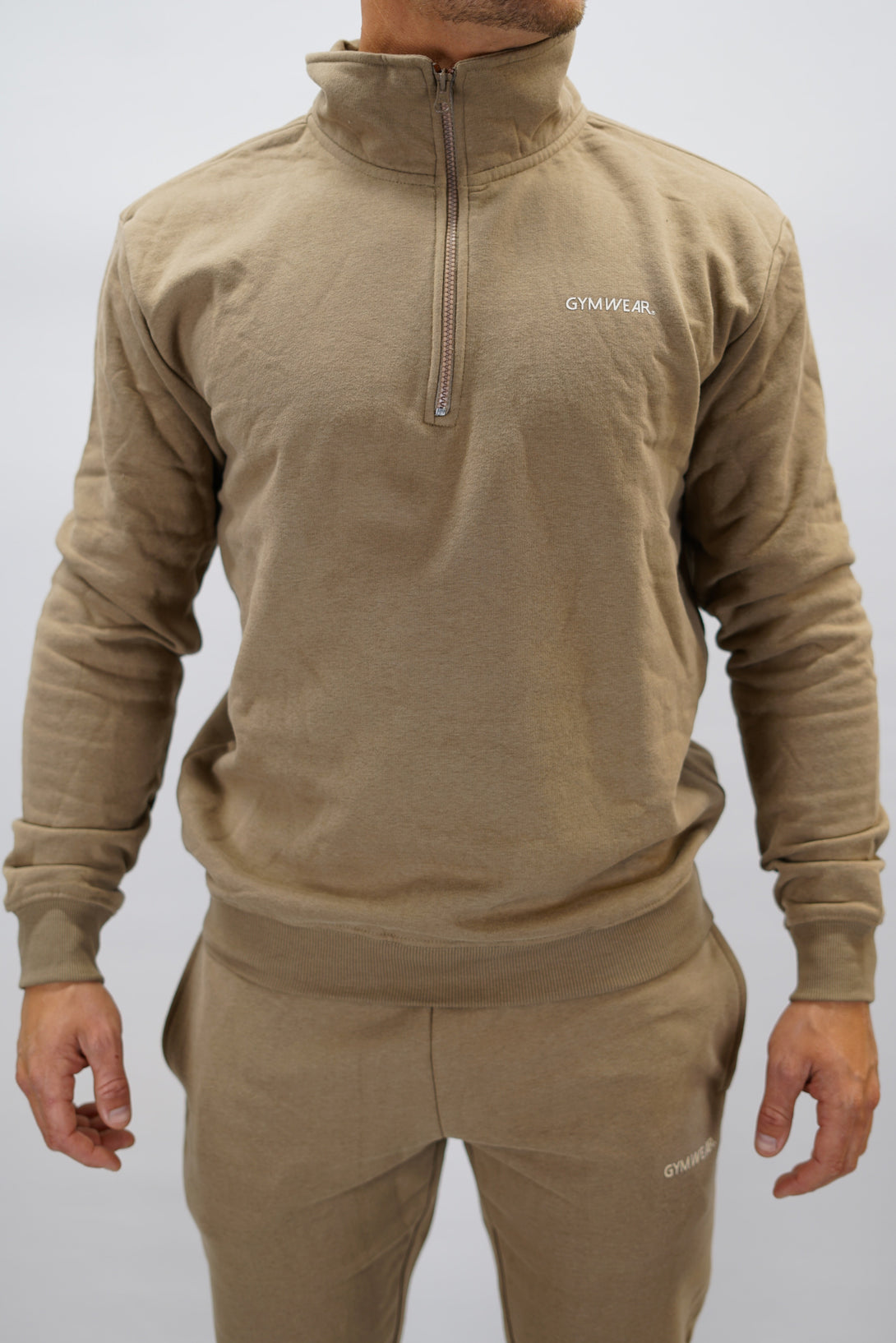Half-Zip Sweater för herr i mjuk borstad bomull, brun färg, med Gymwear logga på vänster bröst och symbol G i nacken. Stilren och funktionell tröja för vardag och aktivitet.
