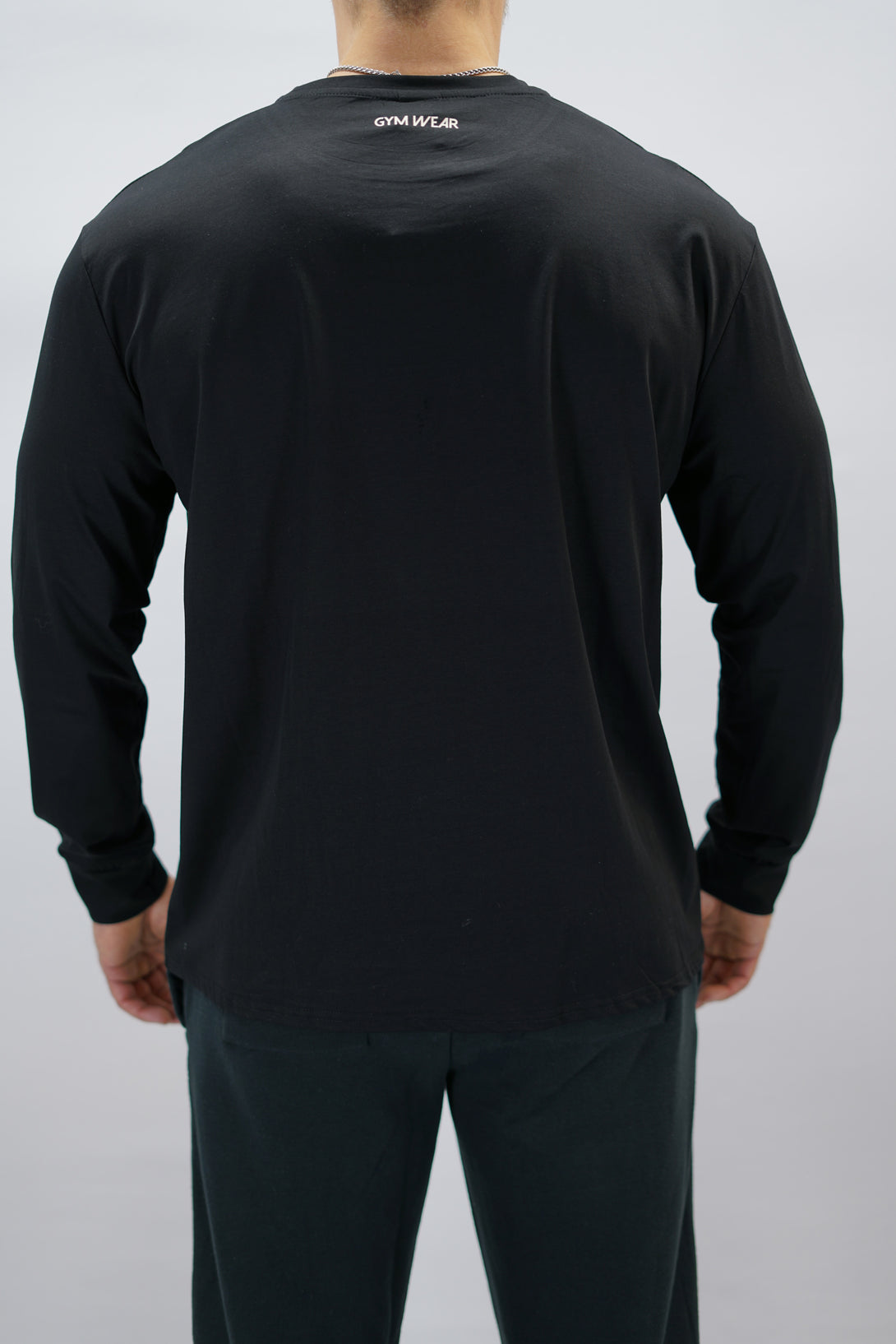 Jace Long Sleeve Shirt, en svart långärmad träningströja med relaxed fit, featuring G-symbol på bröstet och Gymwear-logotyp i nacken, gjord av andningsbara bomull-spandex material