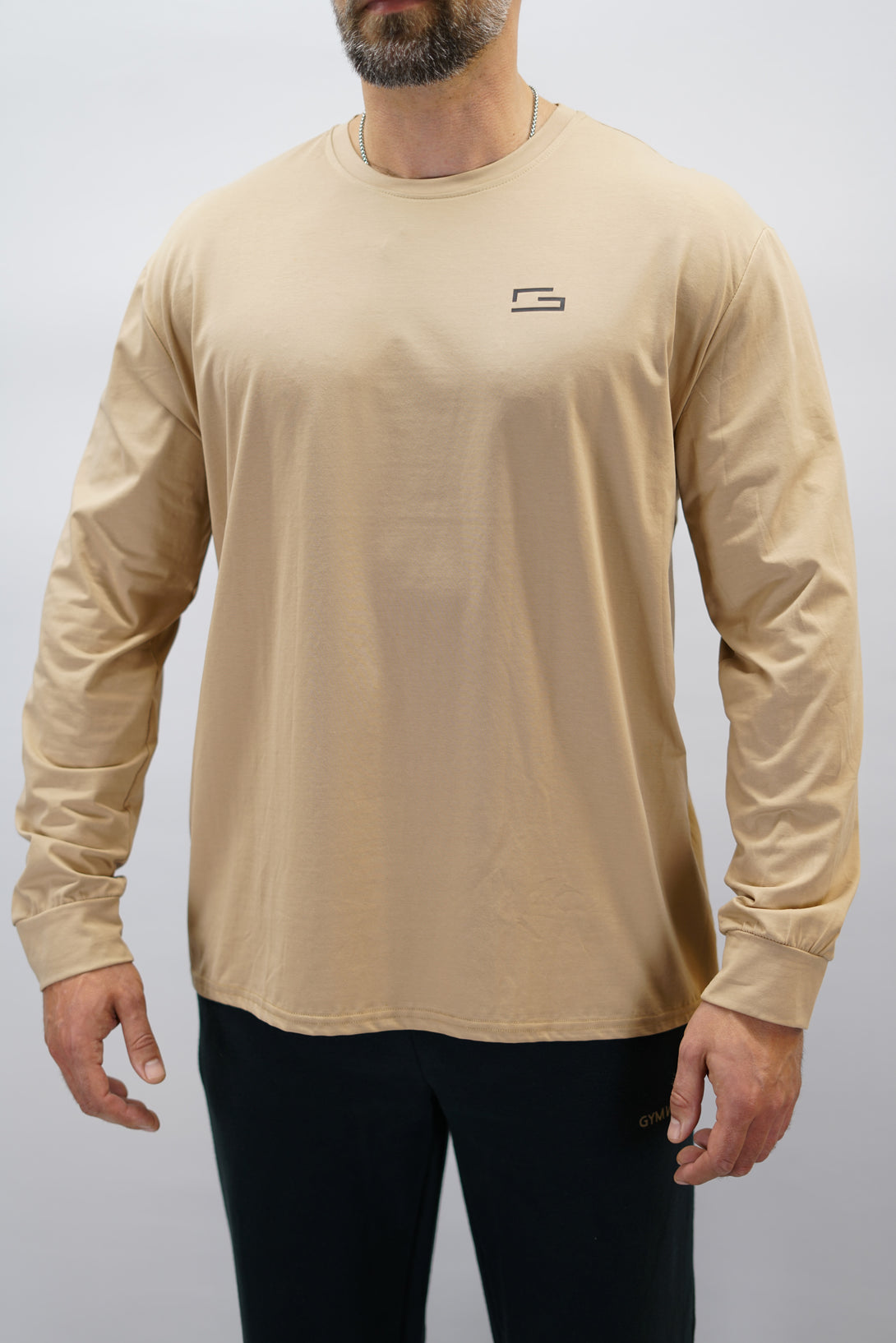 Jace Long Sleeve Shirt, en brun långärmad träningströja med relaxed fit, featuring G-symbol på bröstet och Gymwear-logotyp i nacken, gjord av andningsbara bomull-spandex material