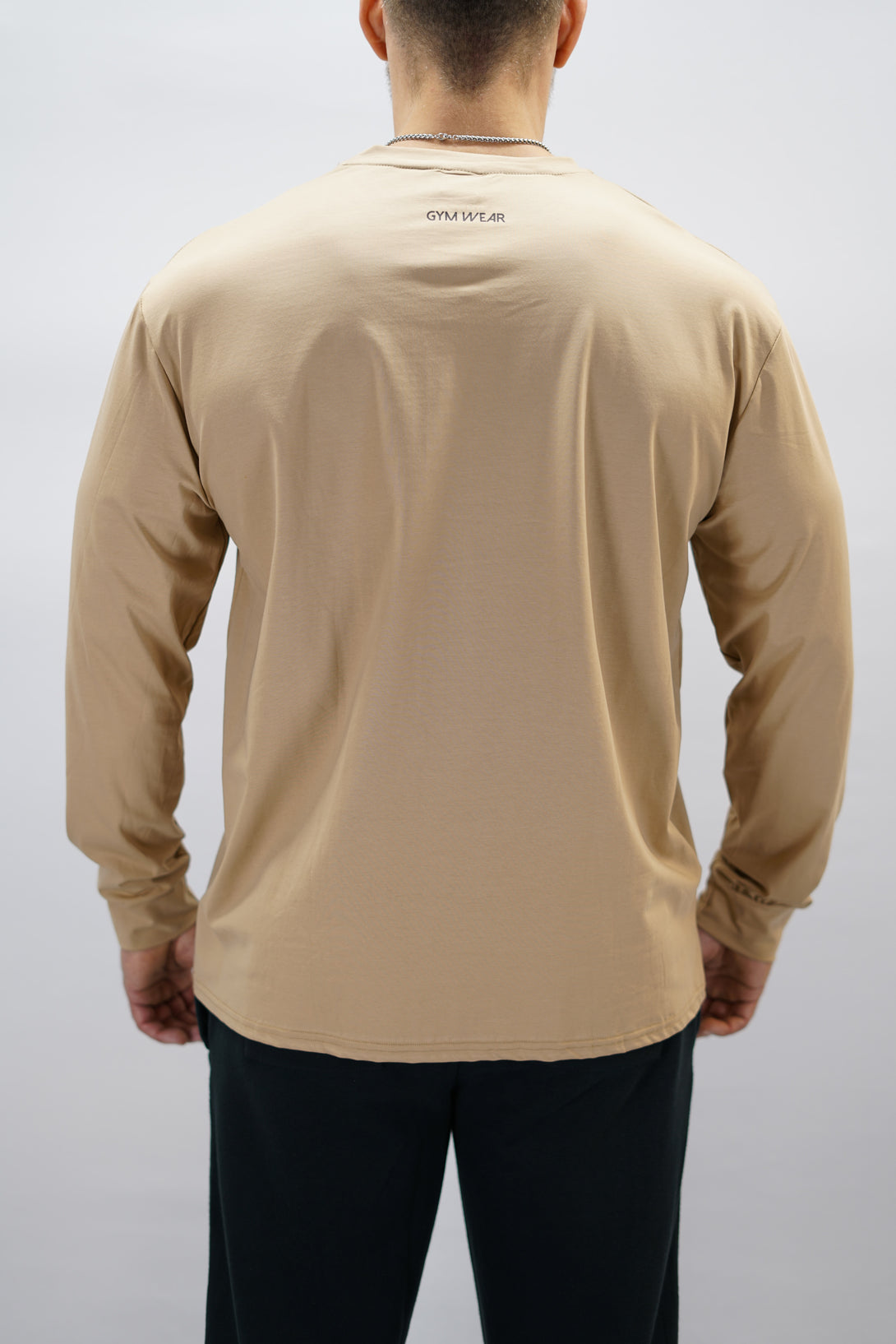 Jace Long Sleeve Shirt, en brun långärmad träningströja med relaxed fit, featuring G-symbol på bröstet och Gymwear-logotyp i nacken, gjord av andningsbara bomull-spandex material