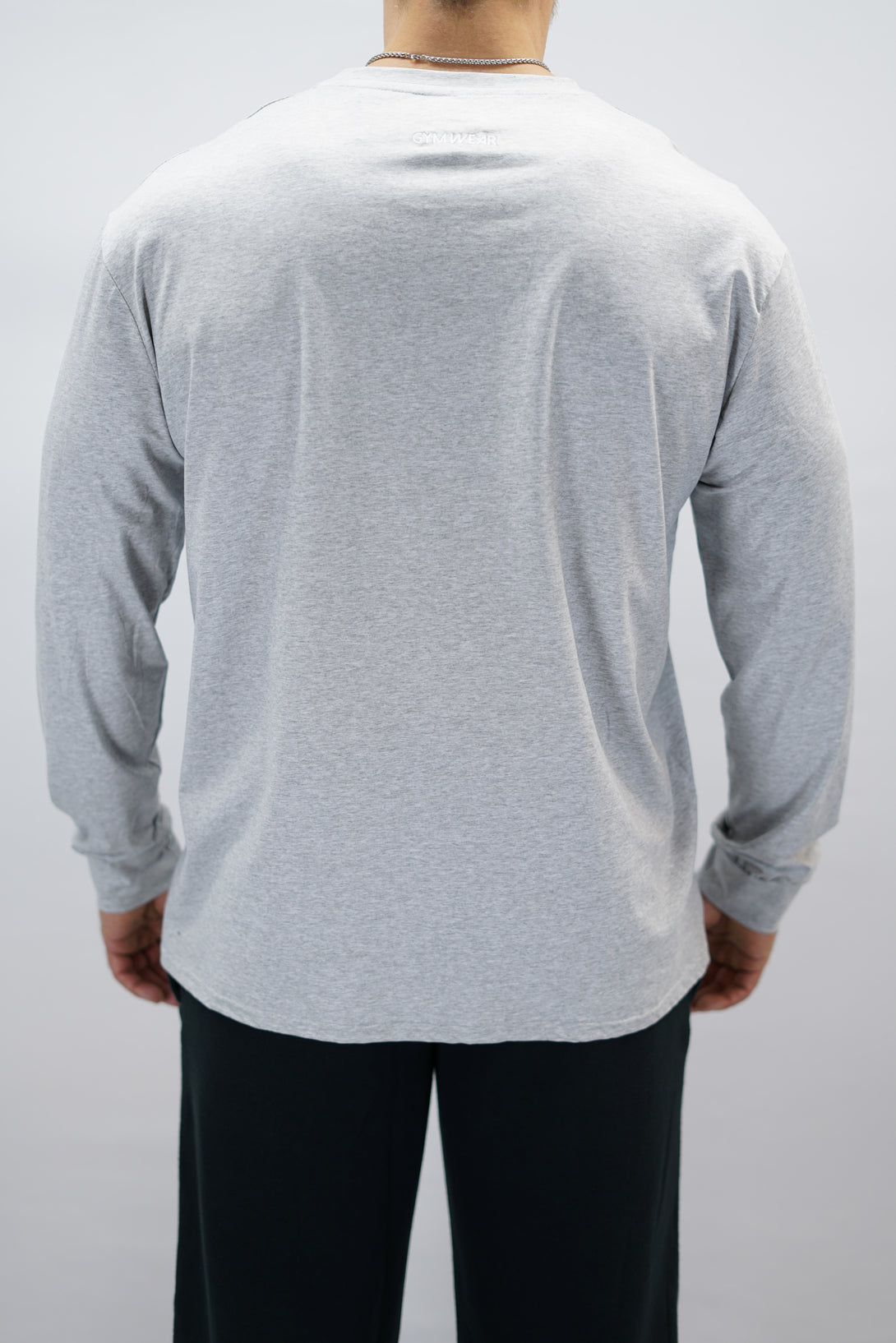 Jace Long Sleeve Shirt, en grå långärmad träningströja med relaxed fit, featuring G-symbol på bröstet och Gymwear-logotyp i nacken, gjord av andningsbara bomull-spandex material