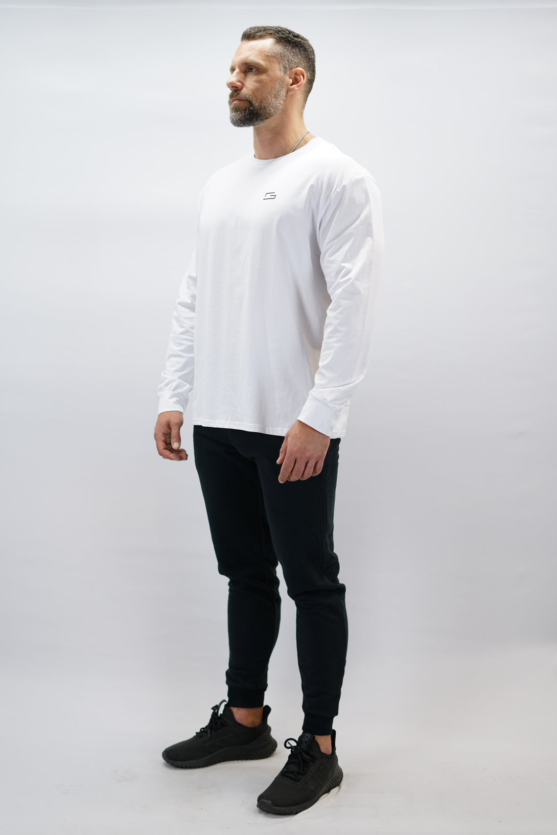 Jace Long Sleeve Shirt, en vit långärmad träningströja med relaxed fit, featuring G-symbol på bröstet och Gymwear-logotyp i nacken, gjord av andningsbara bomull-spandex material
