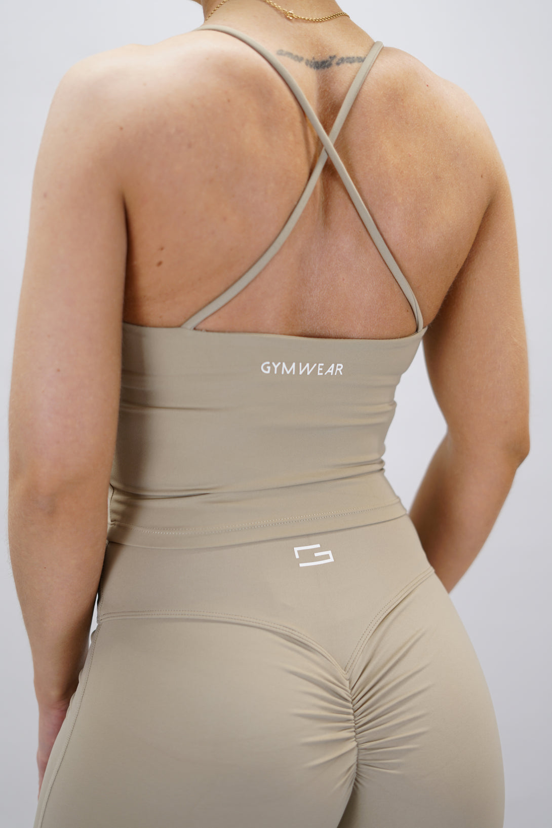 Beige Loana Tank Top - linne med korsade axelband bak och Gymwear-logga på baksidan