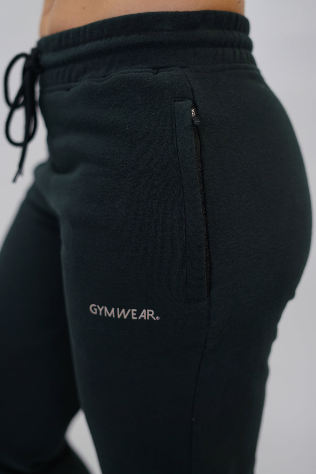 Träningsbyxor för dam i borstad bomull svarta med Gymwear logga på vänster lår nedanför fickan, dragsko och elastisk midja