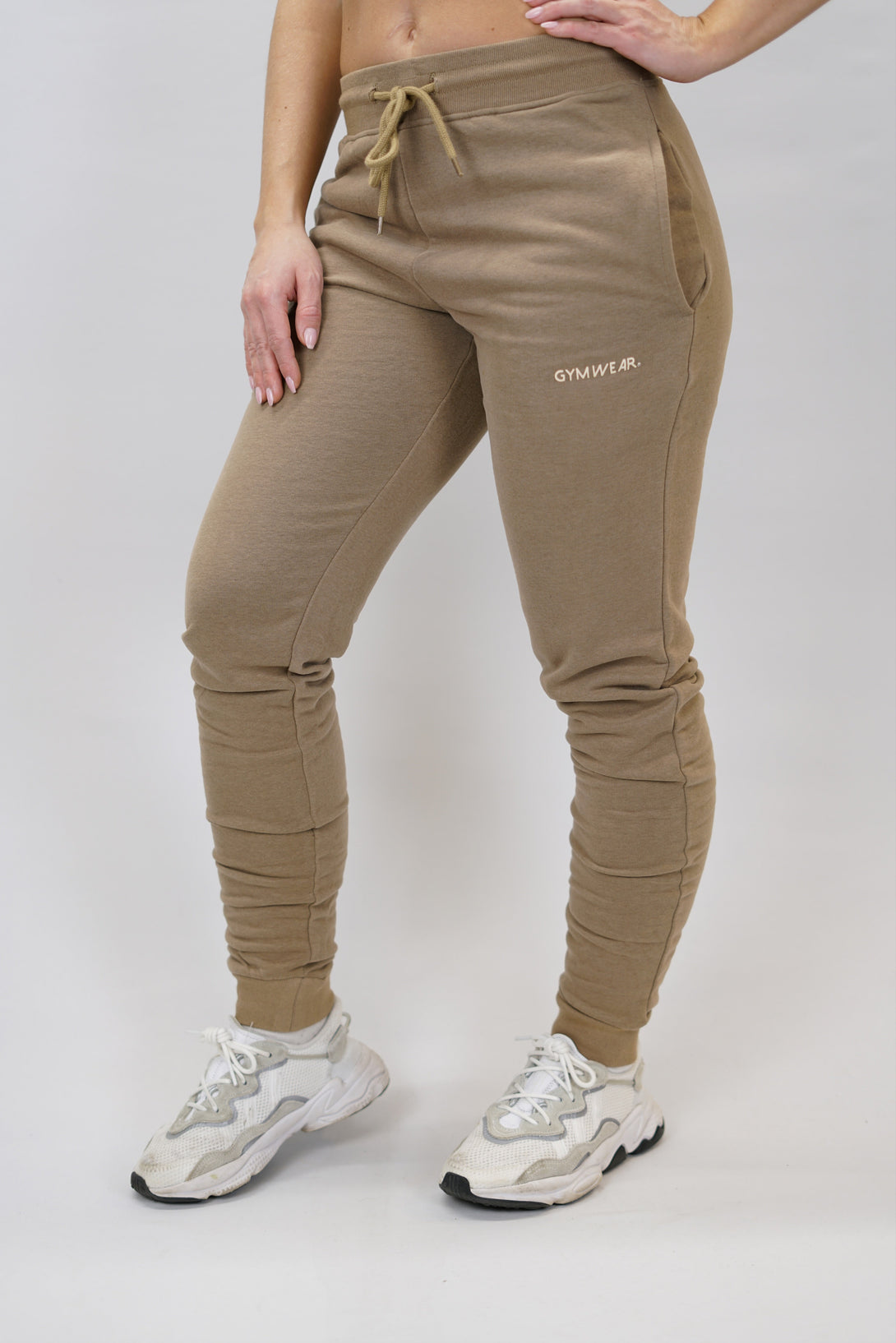 Bekväma joggers i premium borstad bomull. JOGGER RAY har elastisk midja med justerbar dragsko, praktiska sidfickor och avsmalnande passform för en modern look. Perfekta för både träning och vardagsbruk. Brun färg med diskret Gymwear-logga på vänster lår.