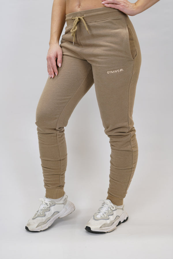 Bekväma joggers i premium borstad bomull. JOGGER RAY har elastisk midja med justerbar dragsko, praktiska sidfickor och avsmalnande passform för en modern look. Perfekta för både träning och vardagsbruk. Brun färg med diskret Gymwear-logga på vänster lår.