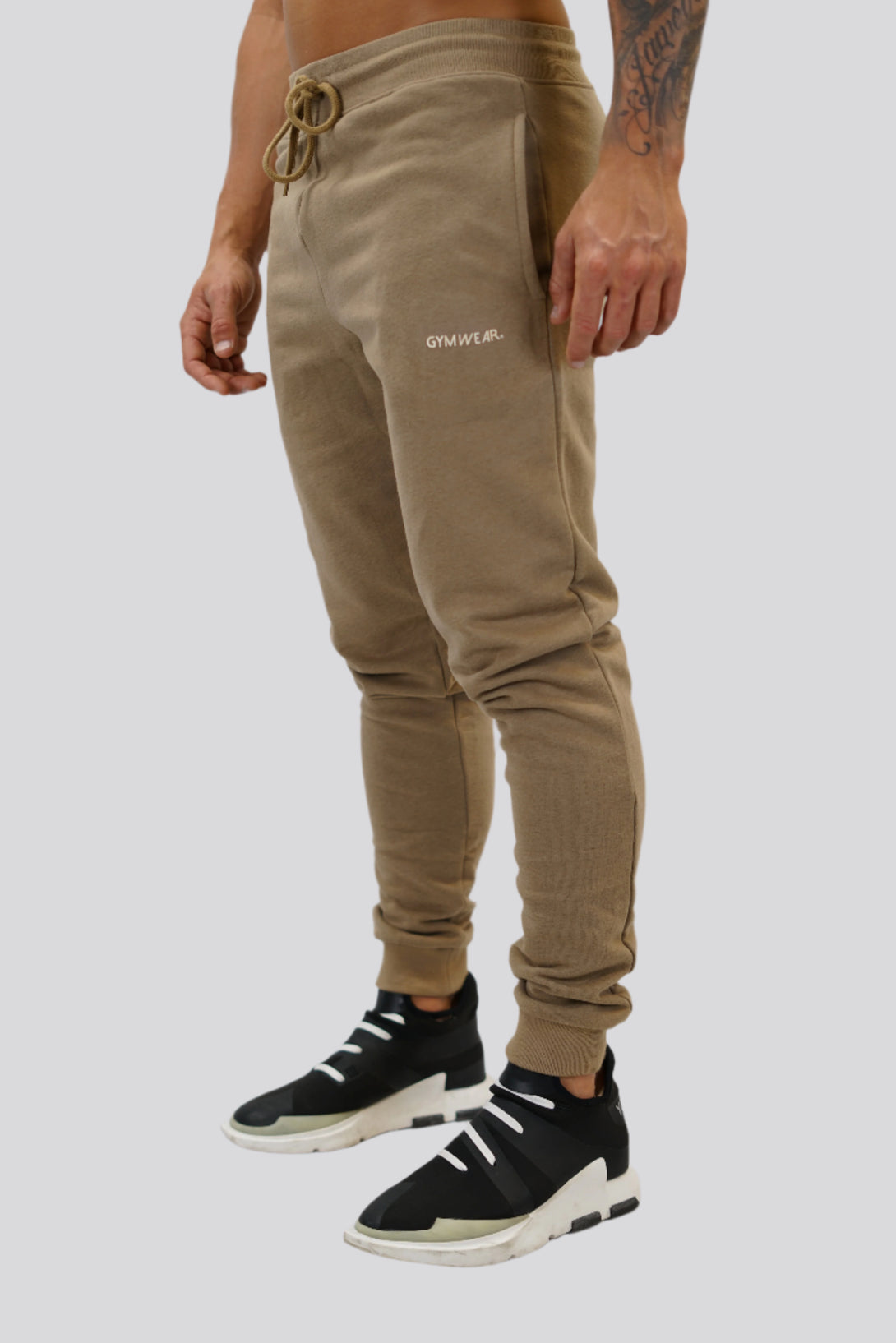 Bekväma JOGGER RAY i premium borstad bomull. Elastisk midja med dragsko, praktiska fickor och avsmalnande passform. Perfekt för träning och vardagsbruk. I färgen brun med Gymwear  logga på vänster lår.