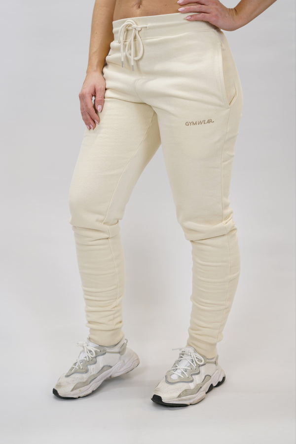 Bekväma JOGGER RAY i premium borstad bomull. Elastisk midja med dragsko, praktiska fickor och avsmalnande passform. Perfekt för träning och vardagsbruk. I färgen beige med Gymwear  logga på vänster lår.