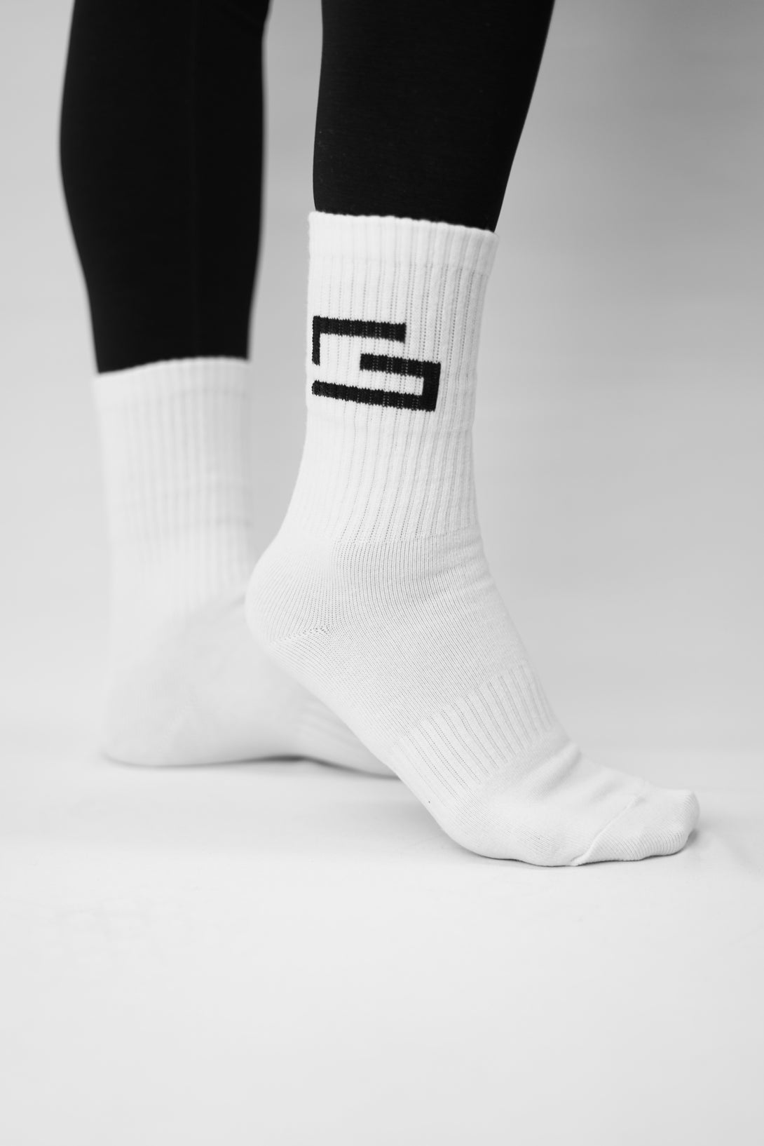 GYMWEAR vita trumpor med broderad G-symbol på vristen – stilren design för träning.